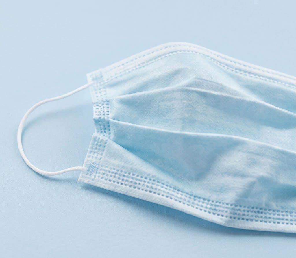 A surgical mask on a plain background